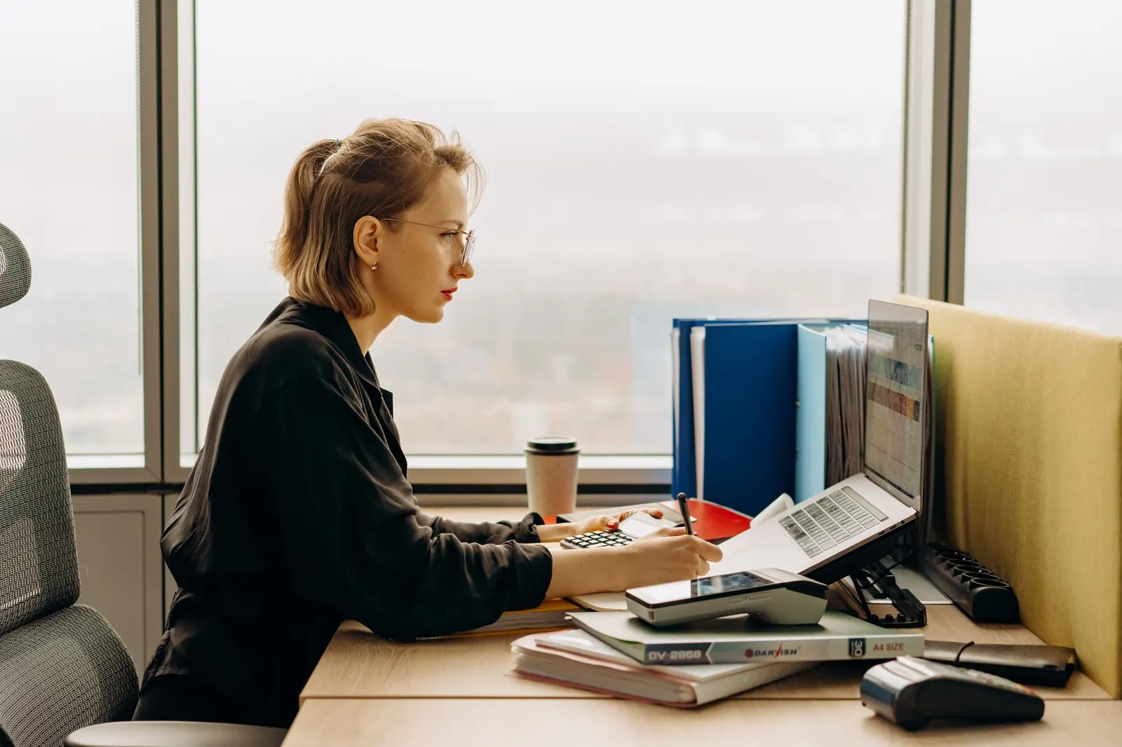 Een accountant aan het werk met dossiers aan haar bureau